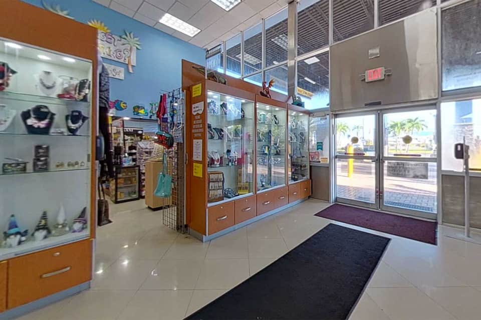 Retail gift shop interior with blue walls, display cases, merchandise on shelves, and glass storefront entrance