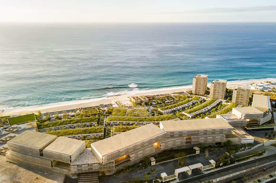 Aerial view of beachfront resort with curved architectural structures overlooking sandy beach and ocean