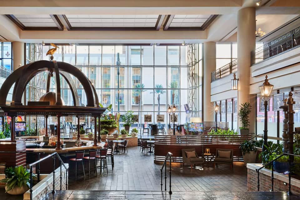 Luxurious hotel lobby atrium with sculptural art piece, multi-level seating areas, and expansive windows