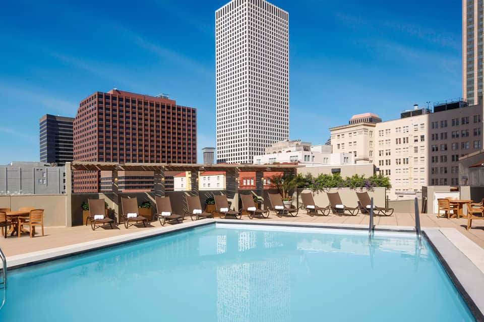 Rooftop pool with lounge chairs overlooking downtown cityscape and tall buildings