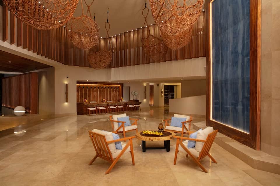 Luxury lobby with woven pendant lights, fireplace, wooden chairs, and modern furnishings on marble flooring