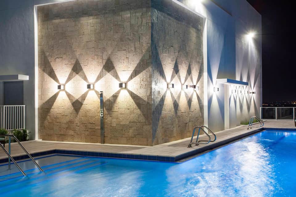 Modern illuminated pool wall at night with geometric lighting patterns