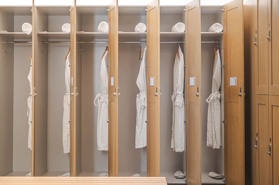 Row of wooden lockers with white robes and towels in spa or fitness facility