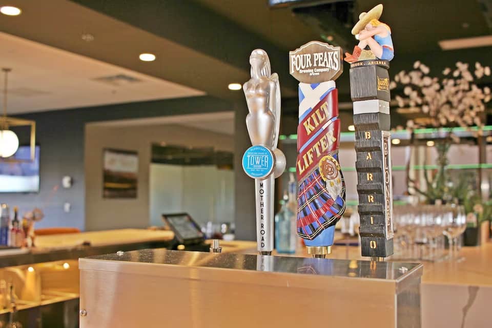 Beer tap handles at bar counter featuring Four Peaks and local craft brewery logos