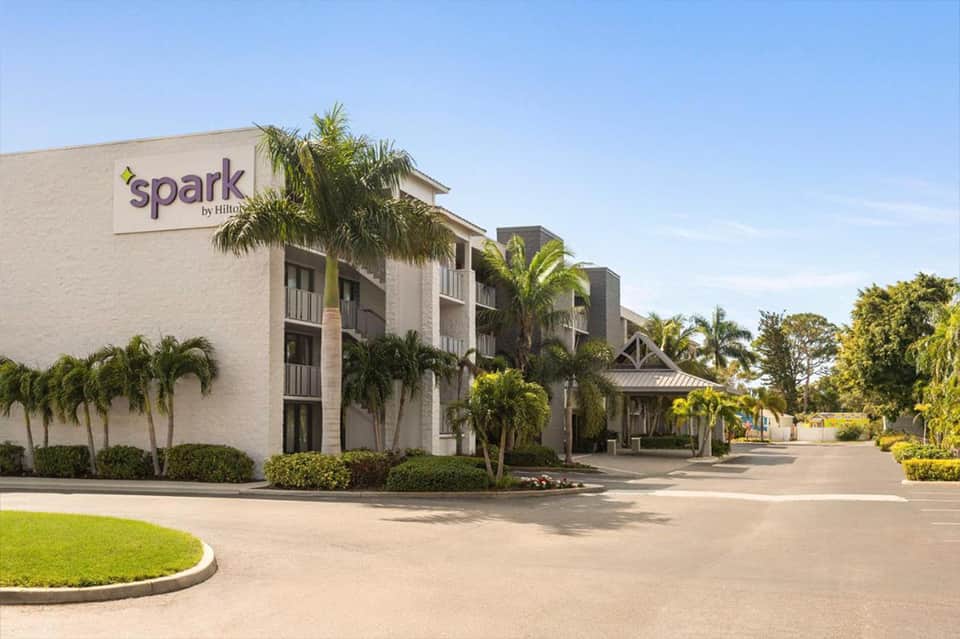 Spark by Hilton hotel exterior with white brick facade and palm trees