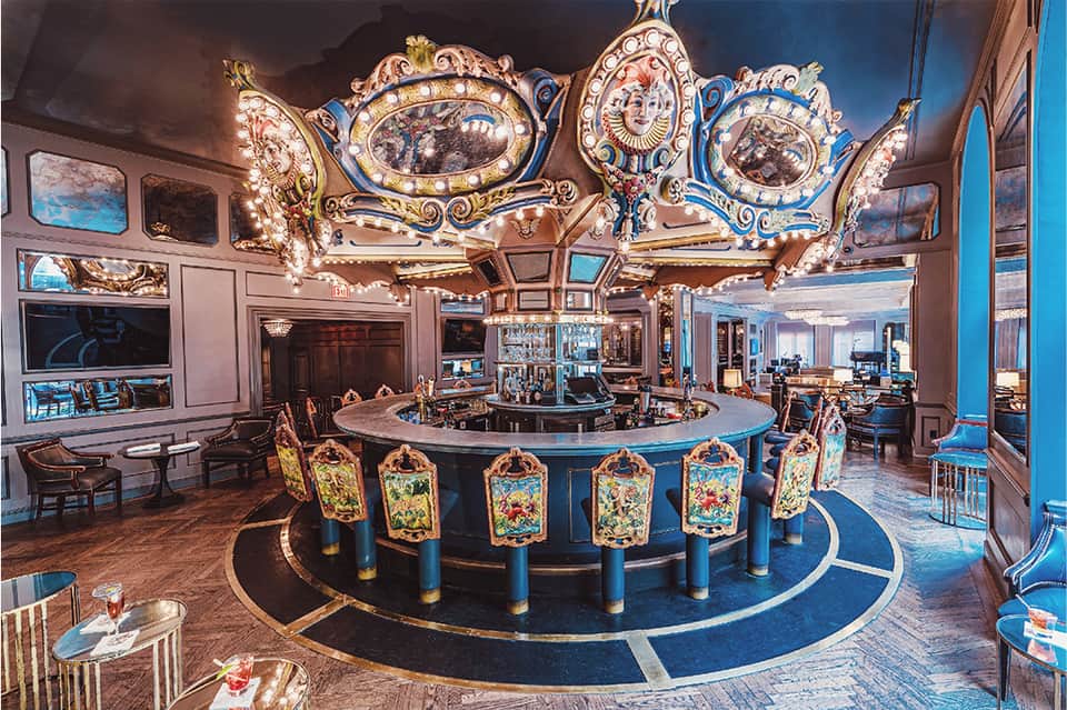 Ornate casino interior with decorative chandeliers, blue bar, and colorful patterned chairs