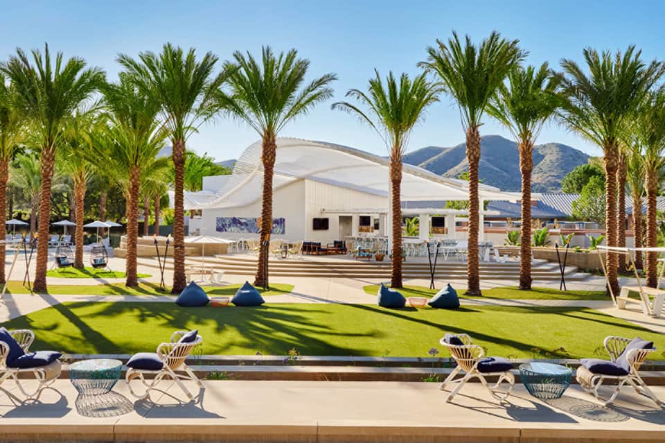 Palm-lined lawn with lounge chairs overlooking mountain views and contemporary white event pavilion