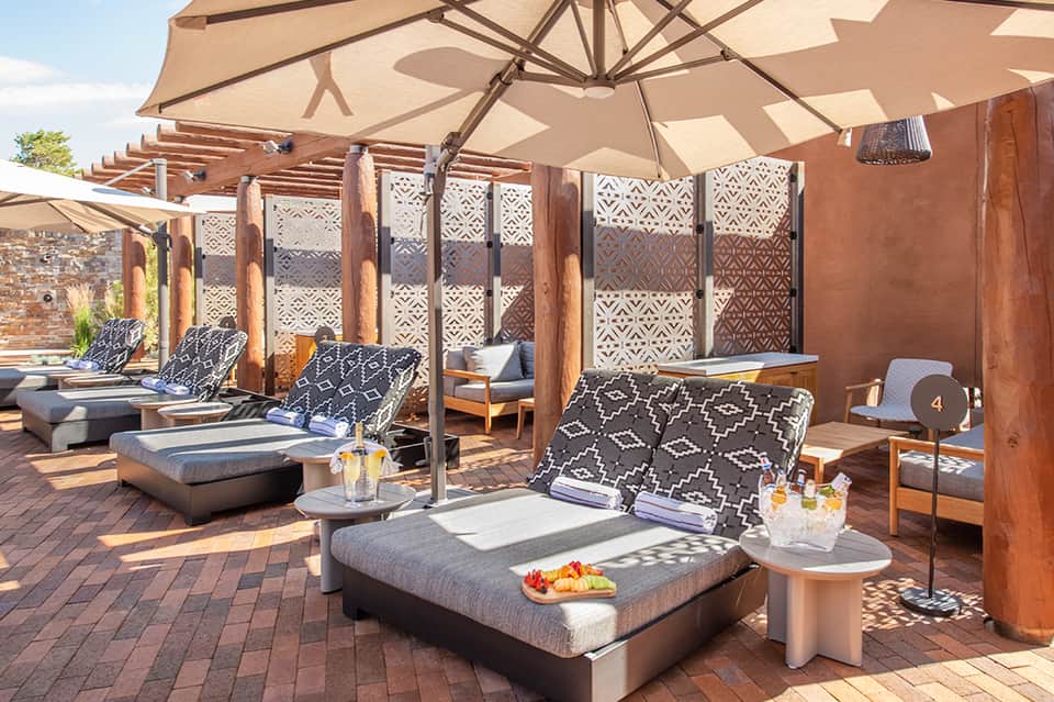 Upscale rooftop lounge with wooden pergolas, sun umbrellas, and geometric patterned seating