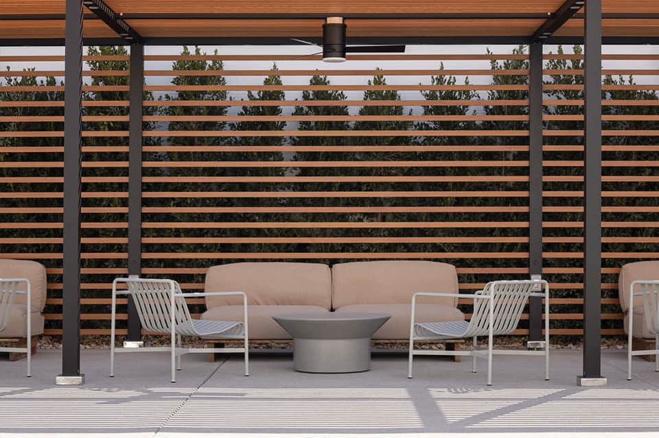 Modern outdoor patio with beige sofa, white chairs, and horizontal wood slat privacy screen
