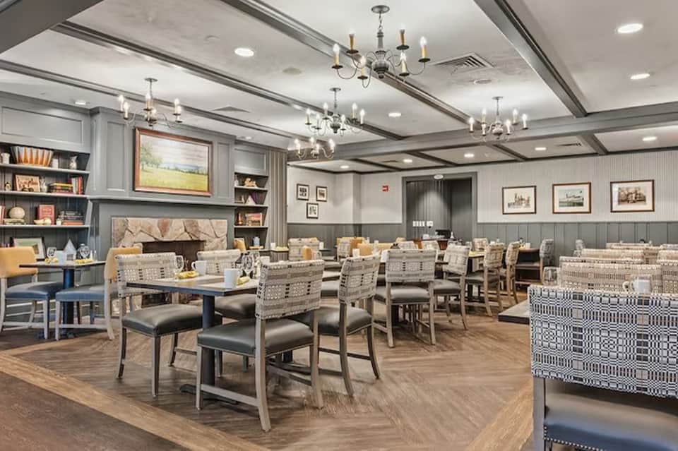Elegant dining room with coffered ceiling, chandeliers, woven chairs, and built-in bookshelves throughout
