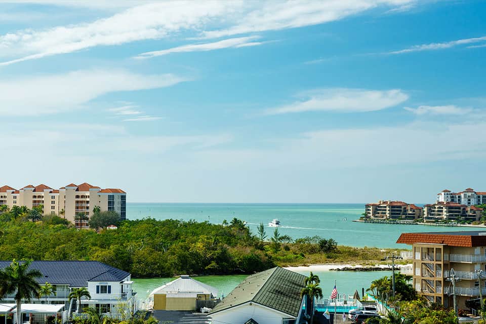 Beachfront resort buildings with turquoise water and tropical vegetation in the background