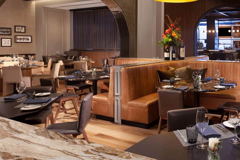 Fine dining restaurant with cognac leather booths, dark tables, and wood accents