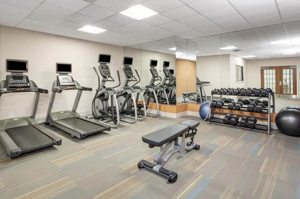 Modern fitness center with treadmills, elliptical machines, weights, and exercise equipment