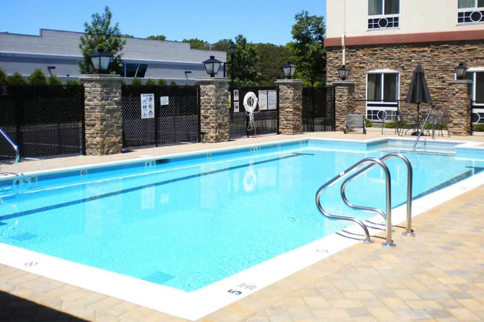 Outdoor swimming pool with metal railings and stone accent walls near residential buildings