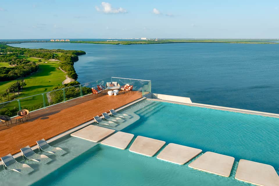 Luxury infinity pool overlooking turquoise bay with lounge chairs and manicured green lawns