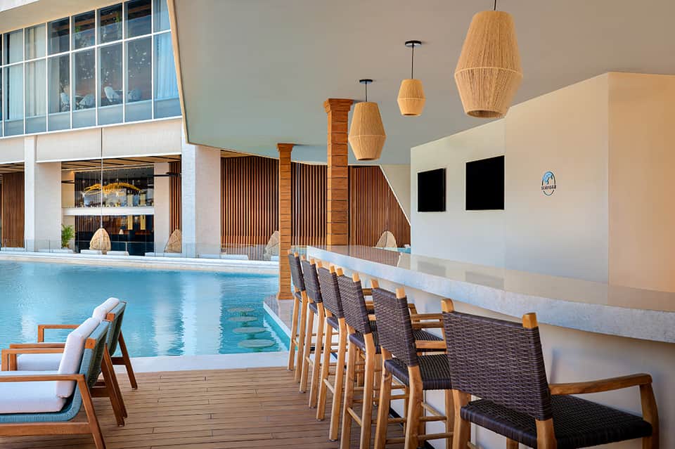 Indoor pool area with wooden pendant lights, seating area, and large windows overlooking facilities