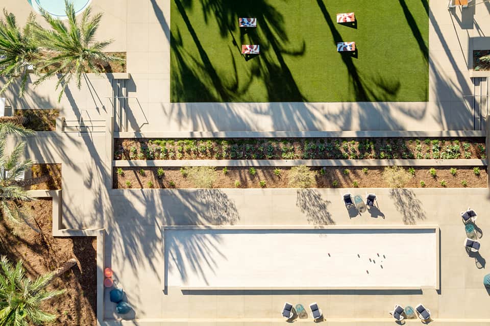 Aerial view of modern courtyard with green lawn, lounge chairs, and planted areas with shadows