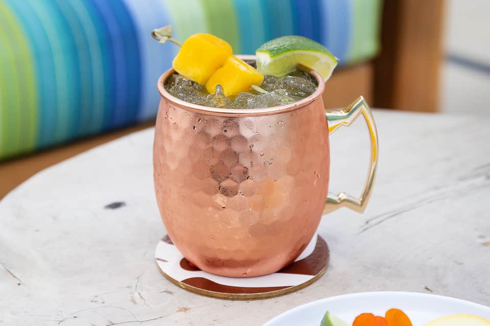 Moscow Mule cocktail in copper mug with lime garnish and ice, served on white surface