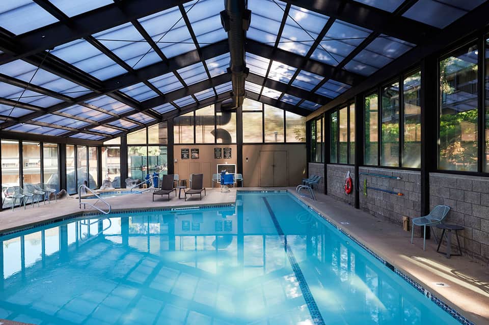 Indoor swimming pool with lane markings under skylight ceiling and glass windows