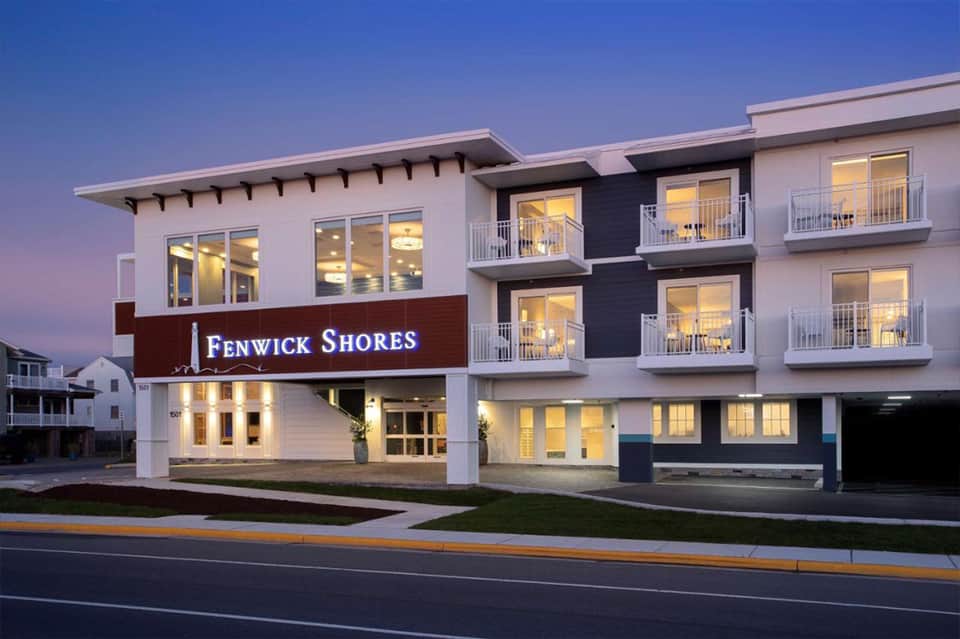 Contemporary three-story hotel building at dusk with Fenwick Shores signage and lit windows