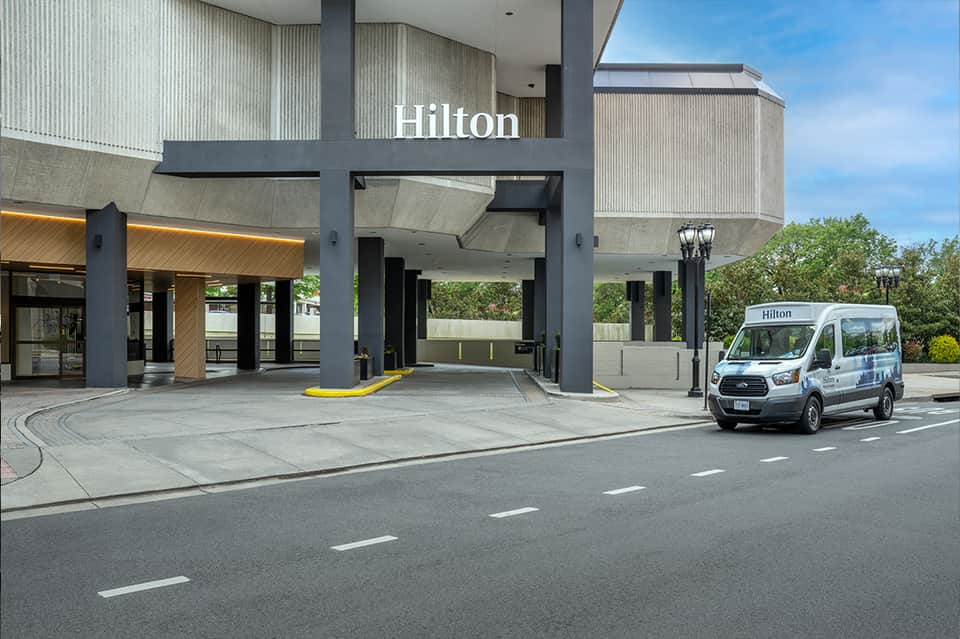 Hilton hotel porte-cochere with contemporary architecture and shuttle van parked outside