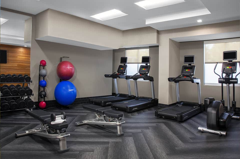 Fitness center with treadmills, exercise bikes, dumbbells, medicine balls, and weight equipment