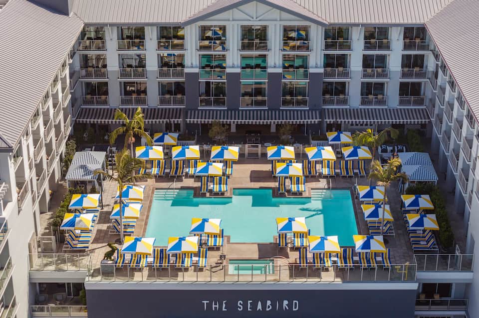 Aerial view of The Seabird hotel courtyard with blue and yellow umbrellas and rectangular pool