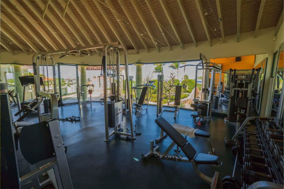 Bright fitness center with exercise equipment and large windows overlooking tropical gardens