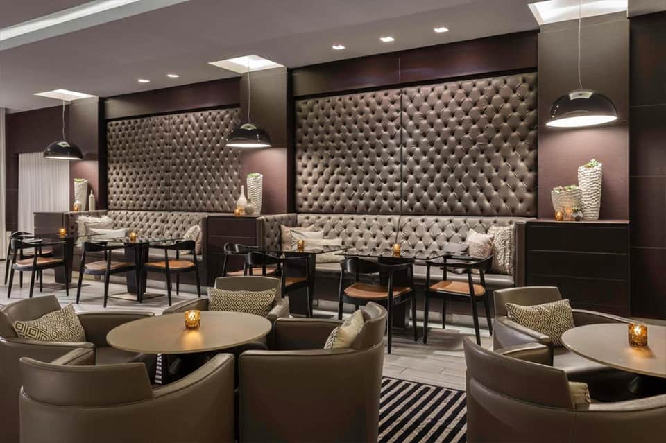 Elegant hotel lounge with tufted seating, pendant lighting, round tables, and modern interior design