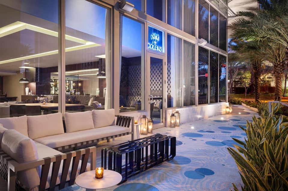 Luxury outdoor terrace at night with modern seating, illuminated glass doors, and decorative lighting