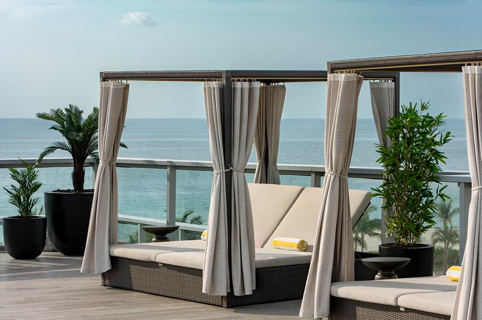Luxury beach resort cabanas with flowing curtains, ocean views, and comfortable daybeds on terrace
