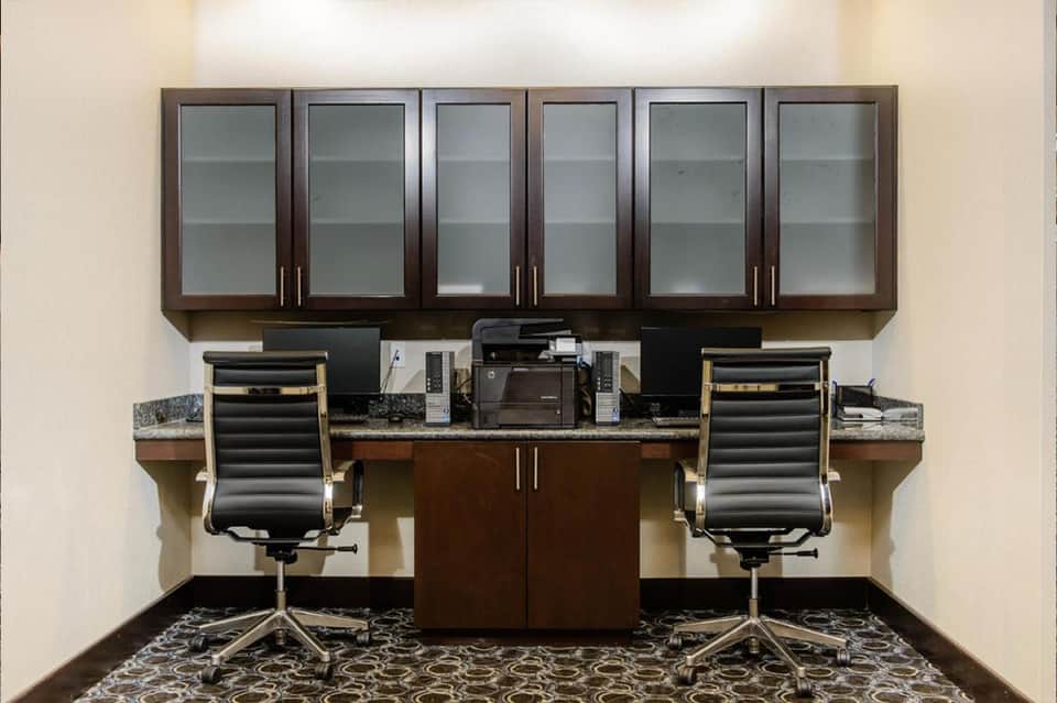 Modern office workspace with dark wood cabinets, dual monitors, and ergonomic black chairs