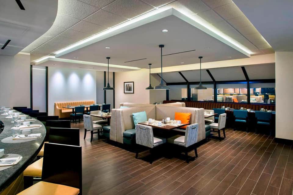 Modern restaurant interior with booth seating, pendant lighting, and ocean-view windows