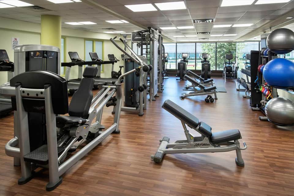 Modern fitness center with cardio machines, weights, exercise balls, and large windows