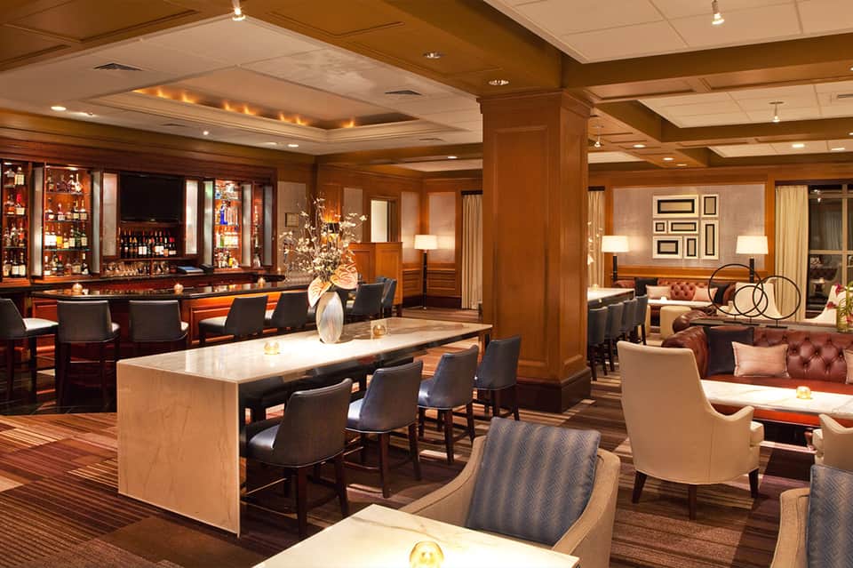 Upscale hotel lounge with wooden bar, leather seating, and elegant furnishings