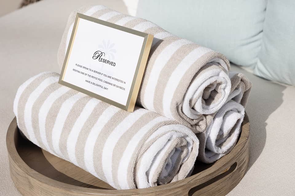 Rolled striped towels in wooden basket with reserved sign on lounge chair