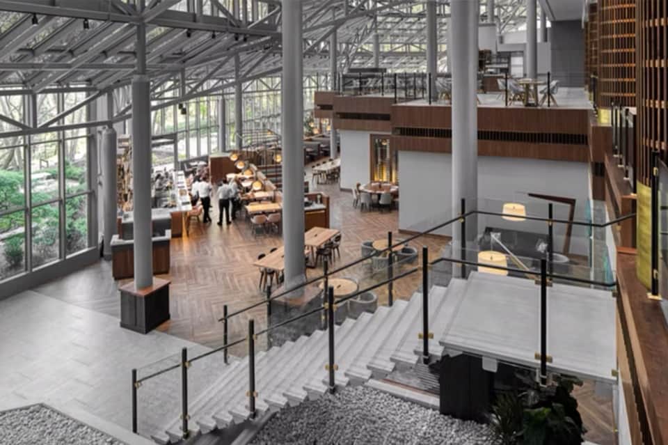 Modern multi-level dining hall with floor-to-ceiling windows and industrial ceiling beams