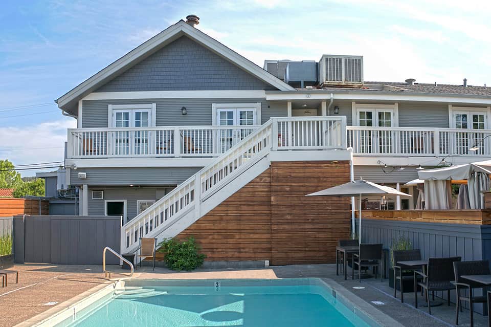 Modern beachfront house with elevated deck, white railings, and illuminated pool in foreground