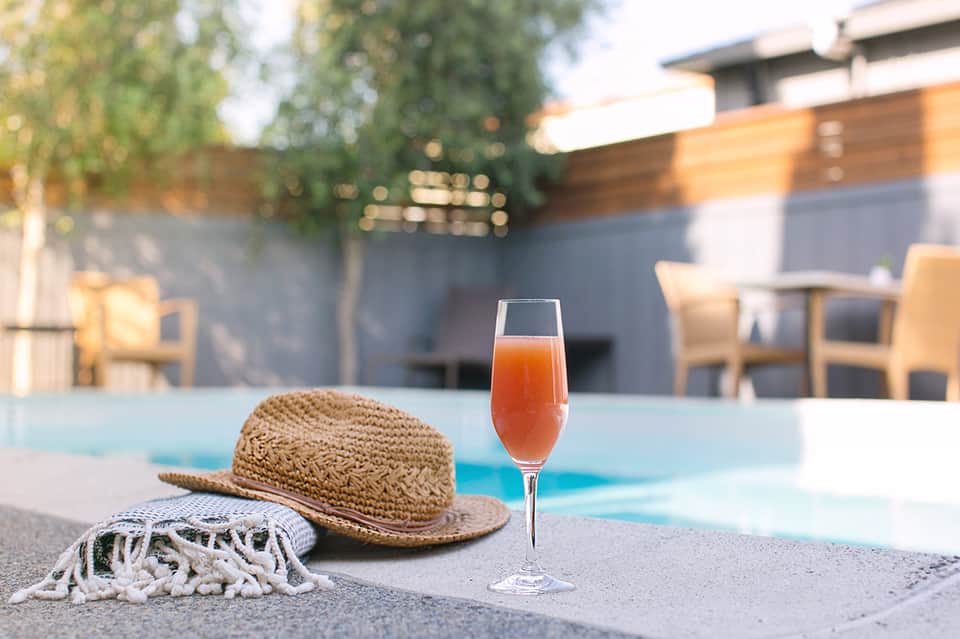 Poolside setting with straw hat, cocktail, and modern resort lounge area