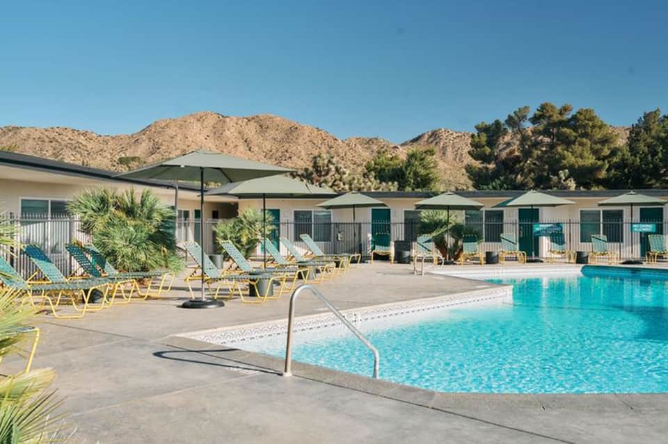 Resort pool with yellow loungers, desert mountains backdrop, and palm trees