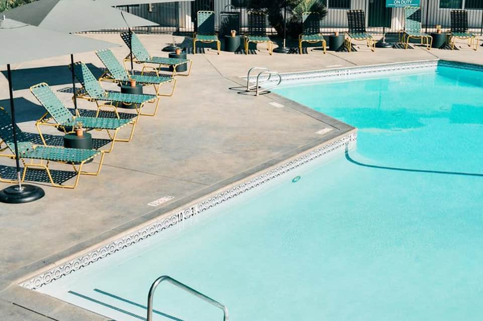 Outdoor swimming pool with turquoise water, teal loungers, and seaside resort setting