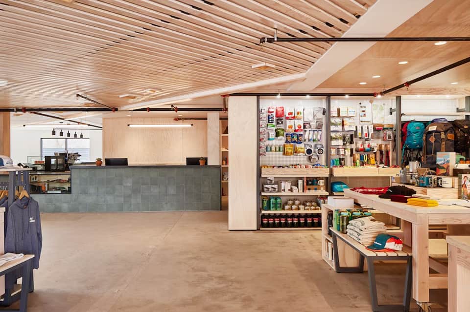 Modern retail shop interior with wooden ceiling, counter, shelving, and merchandise displays