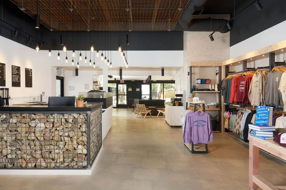 Modern retail shop interior with stone accent wall, pendant lighting, and clothing displays