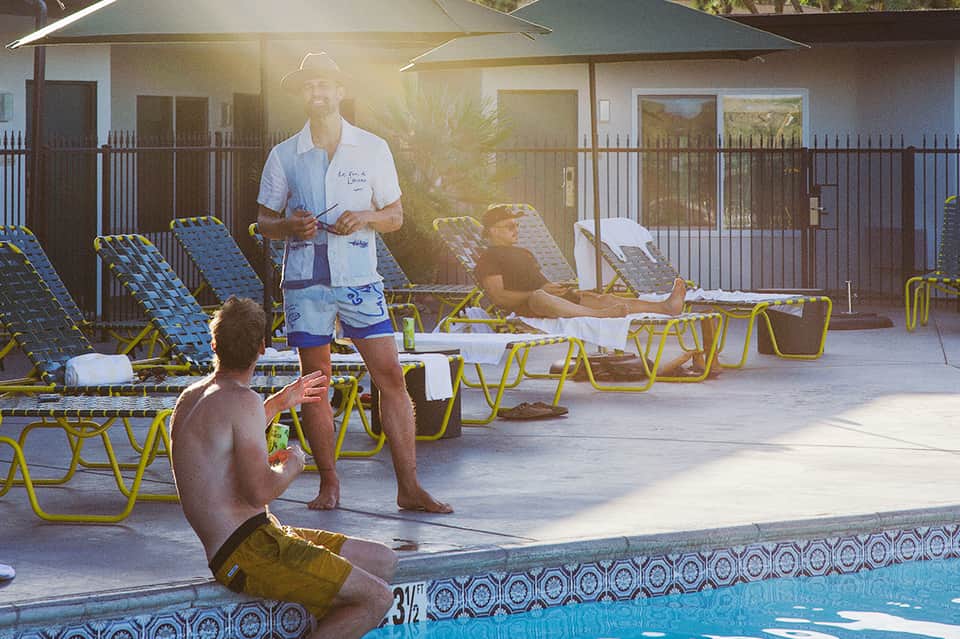Fitness instructor leading outdoor poolside workout class with yellow lounge chairs and modern building