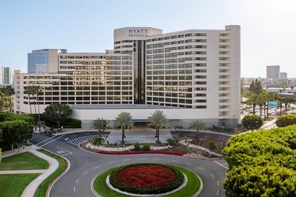 Hyatt Regency hotel exterior with multi-story beige building, manicured landscaping, and palm trees