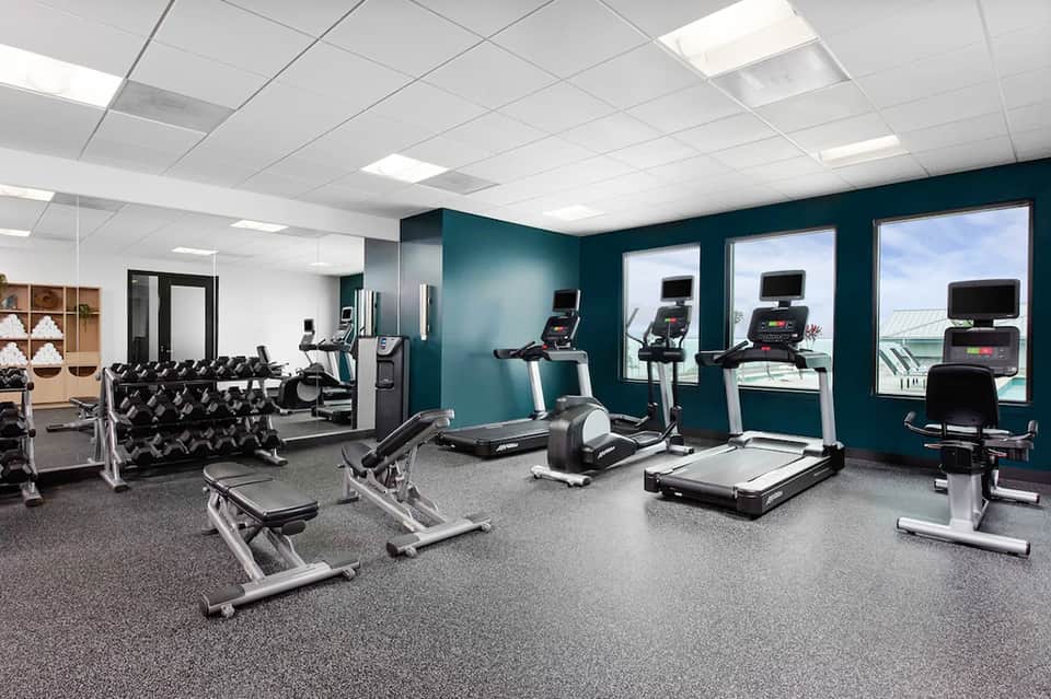 Modern fitness center with cardio equipment, treadmills, and teal accent walls