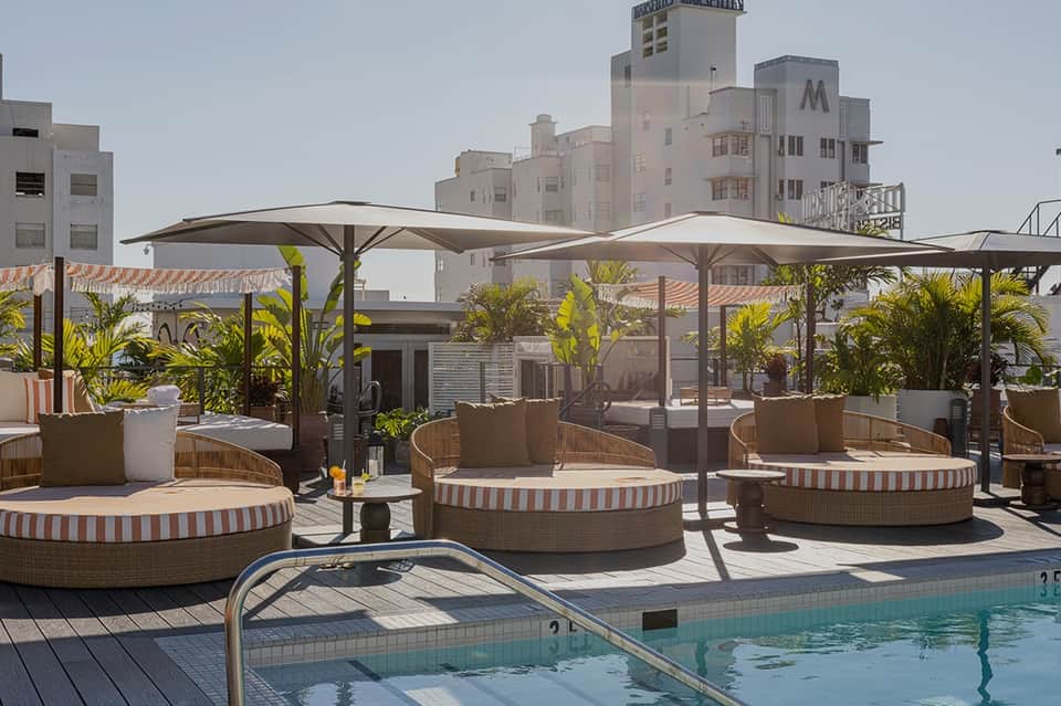Rooftop pool deck with cabanas, shade structures, and city skyline views at a resort hotel