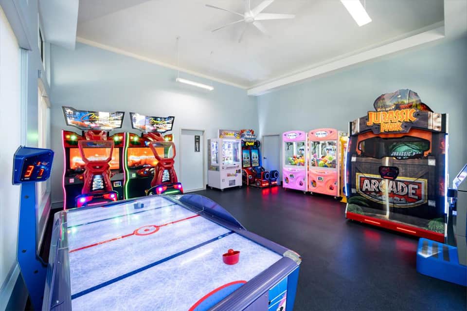 Game room with arcade machines, air hockey table, and Jurassic Park game under bright white ceiling lighting