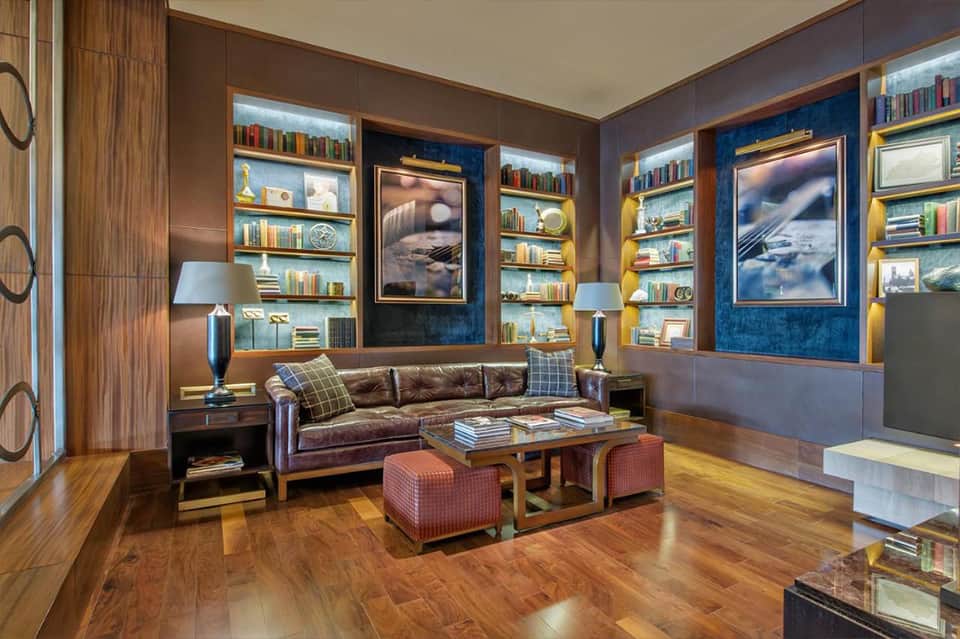 Sophisticated hotel library lounge with leather sofa, illuminated bookshelves, and blue accent walls