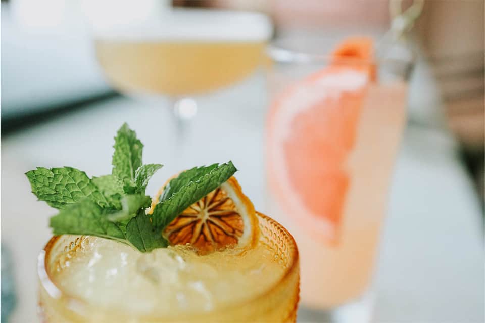 Craft cocktails with citrus garnish and fresh mint on a bar counter